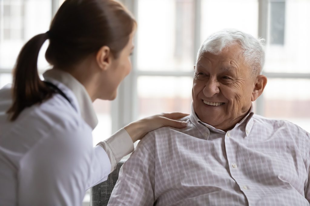 Caring Geriatric Nurse In White Coat Cares For Elderly Man